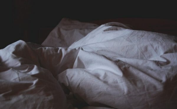 睡眠不足でなかなか布団から出てくられずにいる様子のイメージ