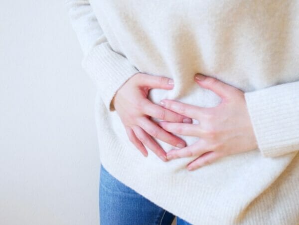 プロテインを飲みすぎてお腹にガスが溜まっている女性のイメージ