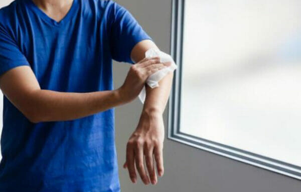 自転車通勤のあとにかいた汗を汗拭きシートでぬぐう男性のイメージ